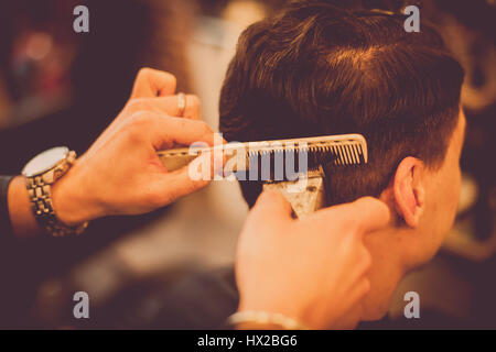 Close up shot of a hair stylist using a comb and a razor on a client. Stock Photo