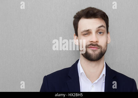 Young handsome man in a black suit laughing against gray textured wall Stock Photo