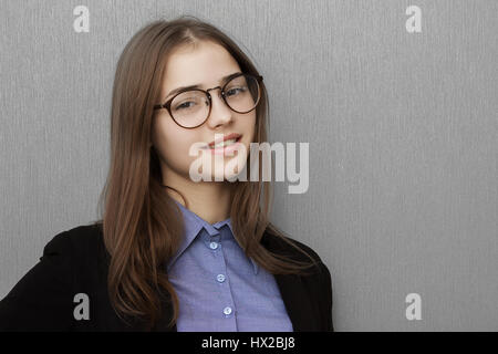 Scholarly looking middle-aged woman wearing heavy rimmed glasses and a black jacket standing with folded arms looking at the camera with a serious expression Stock Photo