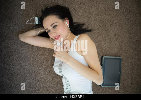 Woman listening music in headphones on carpet Stock Photo