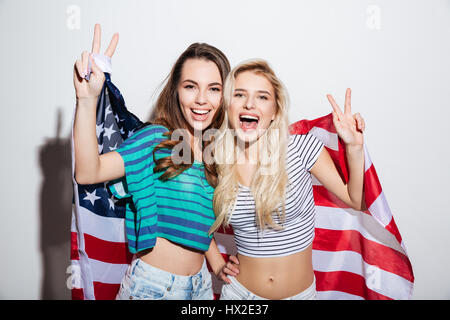 Portrait of two cheerful happy girls standing and holding usa flag isolated on the white background Stock Photo