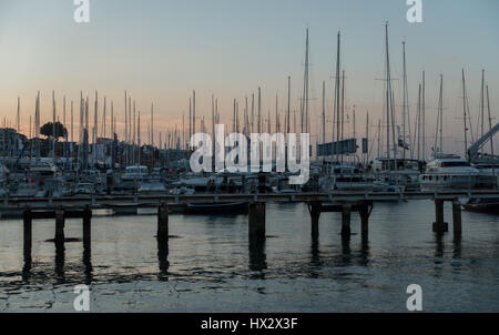 many masts silhouette against a sunset over Cowes Harbour Marina on a quiet still duskwith quay post and calm water, Cowes Week regatta, Cowes UK Stock Photo