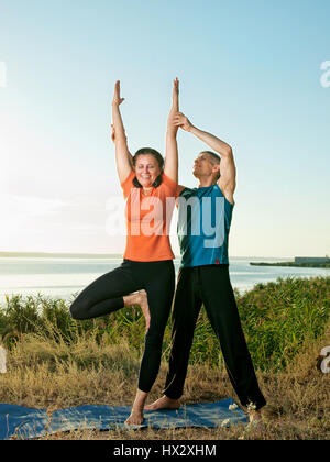 smiling couple making yoga exercises outdoors Stock Photo