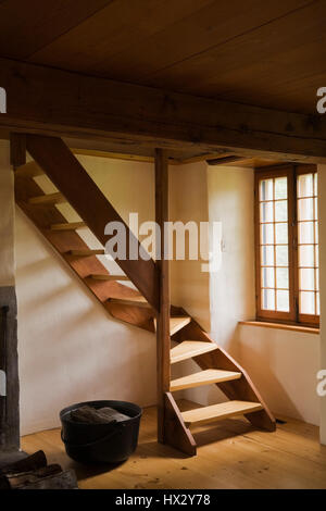 New twisting wooden stairs next to black cast iron pot in 1780 old house interior Stock Photo