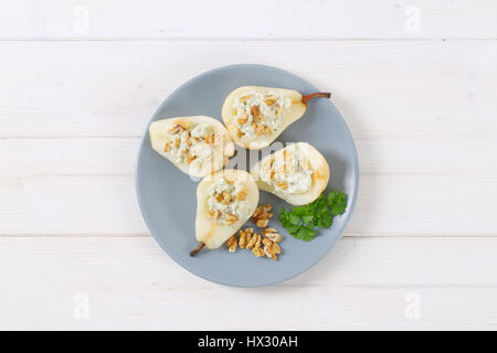 plate of halved pears with blue cheese and walnuts on white background Stock Photo