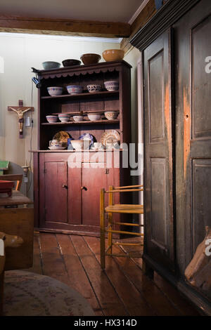 Tall wooden brown antique armoire and brown buffet with crockery and china in antique store located in 1810 old house interior Stock Photo