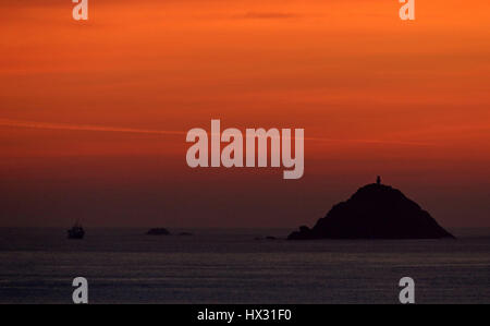 The sun sets behind Irish Lights Vessel Granuaile as it is anchored off Black Rock Ireland off the West Coast of Co. Mayo, Ireland as dive teams have begun searching the wreckage of an Irish Coast Guard helicopter for its three missing crew after it crashed into the Atlantic over a week ago. Stock Photo