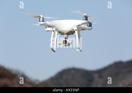 White remote controlled Drone Dji Phantom4 Pro equipped with high resolution video camera hovering in air and blue sky in the background Stock Photo