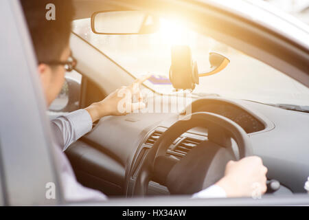 Business Man in the car and using mobile phone with map gps navigation, toned at sunset. Stock Photo