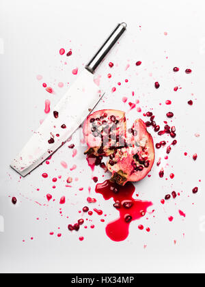 Pomegranate chopped with a cleaver on white background Stock Photo