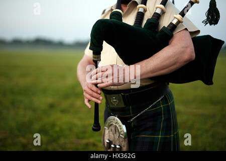A musician plays the bagpipes in the fields. Fingers and bagpipe close up. Stock Photo