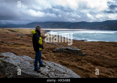 A walker looks out as waves break on Maghera beach near Ardara, County Donegal, Ireland part of Ireland's Wild Atlantic Way Stock Photo