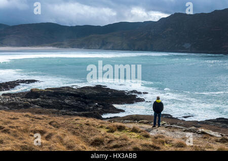 A walker looks out as waves break on Maghera beach near Ardara, County Donegal, Ireland part of Ireland's Wild Atlantic Way Stock Photo