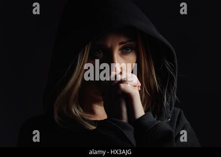 Praying woman in hood. Nun. Stock Photo