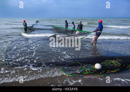 Filipino fishermen haul their seine fishing net out of the water at BayBay Beach, Roxas City, Panay Island, Philippines. Stock Photo