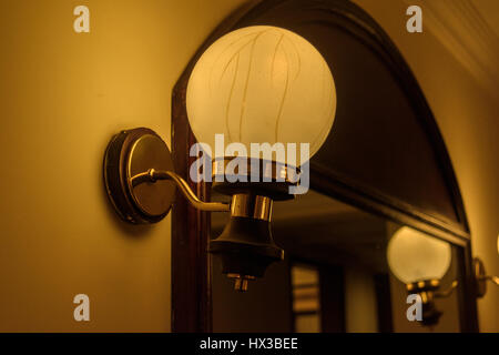 interior lamp with warm light against plaster wall and blurry mirror reflection background Stock Photo