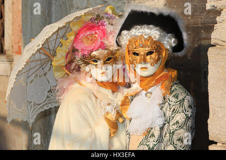 A couple in traditional Venetian masks outside the Doge's Palace during the Carnival in Venice, Italy Stock Photo