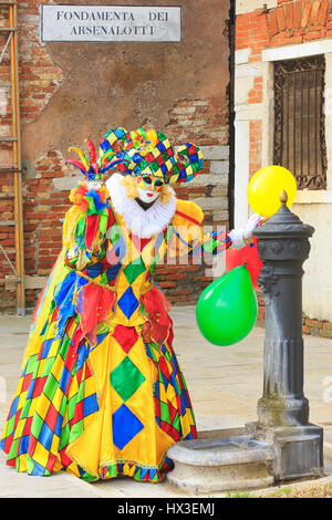 A colorful harlequin (clown) outside the Venetian Arsenal during the Carnival of Venice, Italy Stock Photo