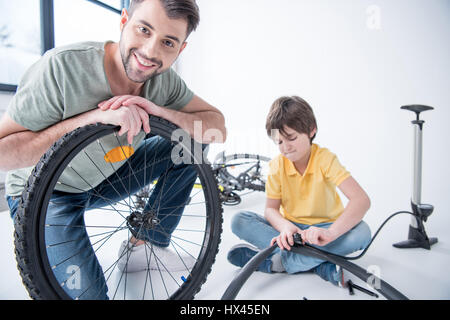 Son and father repairing bicycle tire in studio on white Stock Photo