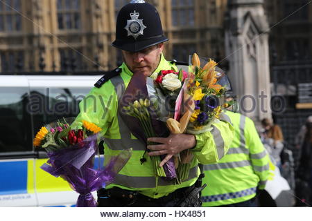 Westminster, London, UK. 24th March, 2017. A policeman carries flowers across the road at Westminster London this afternoon. Credit: reallifephotos/Alamy Live News Stock Photo