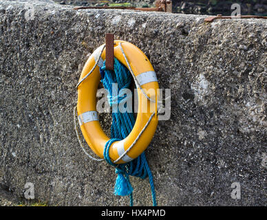A luminous life saving ring and buoyancy hangs on the harbor wall in Ballintoy on the North Coast of Ireland Stock Photo