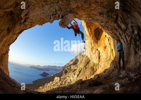 Rock climbers: one man lead climbing on ceiling in cave, another belaying Stock Photo
