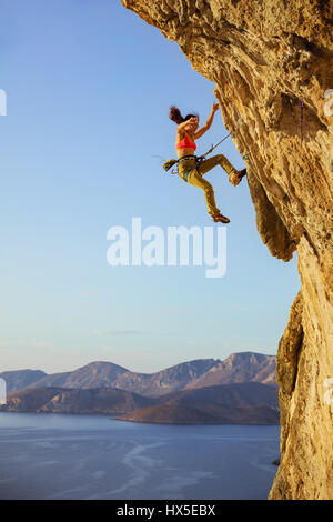 Female rock climber falling off cliff while lead climbing, chipped off piece of cliff falling near woman's foot Stock Photo