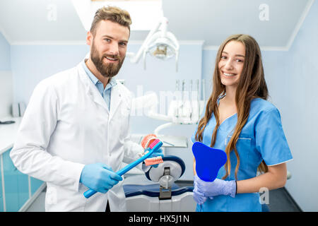 Portrait of handsome dentist with young female assistant in uniform at the dental office Stock Photo