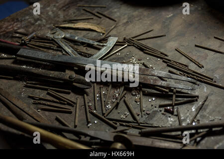 Collection of old basic and rusty jewellery making tools and drill bits on a wooden bench. Stock Photo