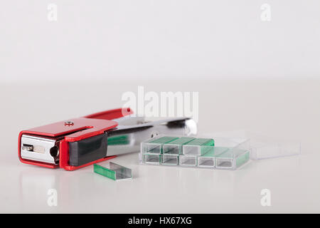 Red stapler and green staples isolated on white background. Stock Photo