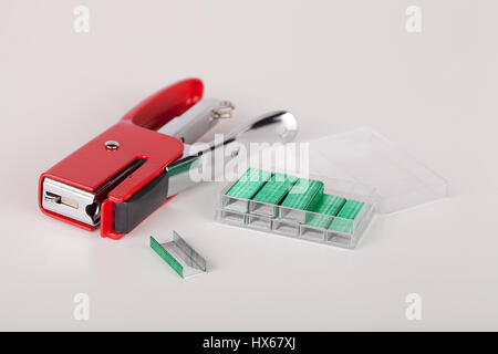 Red stapler and green staples isolated on white background. Stock Photo