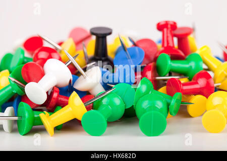 Pile of colorful pushpins on a white surface. Pile of thumbtacks isolated on white background. Stock Photo