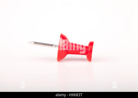 Red pushpin on a white surface. Push pin isolated on white background. Stock Photo