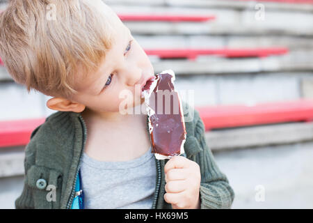 Kid eating chocolate ice-cream outdoor, close up Stock Photo