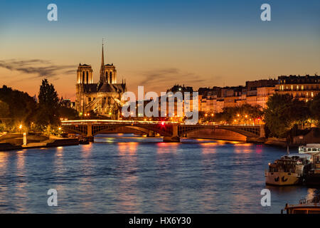 Notre Dame de Paris Cathedral, Seine River and the Ile Saint Louis at twilight. Summer evening with the Sully Bridge and city lights in Paris Stock Photo