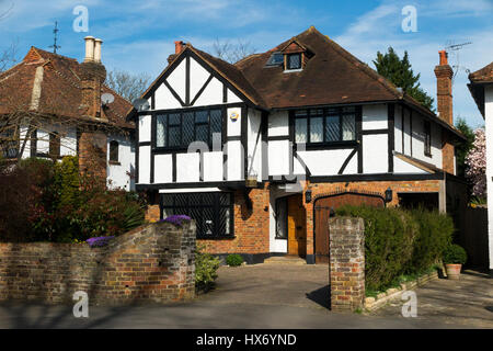 Mock Tudor black and white 1930's house with garage and a drive, in Esher, Surrey. UK. Photograph taken on a sunny day with sun and blue sky. Stock Photo