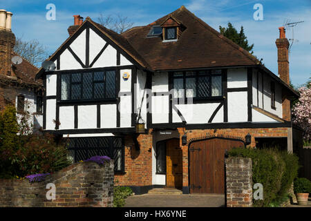 Mock Tudor black and white 1930's house with garage and a drive, in Esher, Surrey. UK. Photograph taken on a sunny day with sun and blue sky. Stock Photo