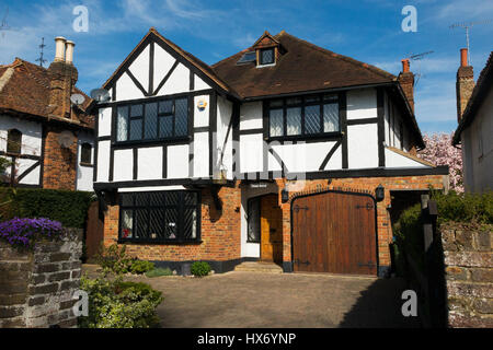 Mock Tudor black and white 1930's house with garage and a drive, in Esher, Surrey. UK. Photograph taken on a sunny day with sun and blue sky. Stock Photo