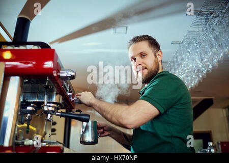The barman, barista, makes a hot coffee drink at  bar counter in Stock Photo