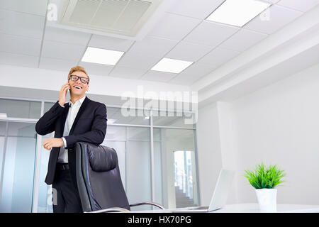 Businessman in glasses standing  front of desk office talking on Stock Photo