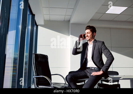Businessman sitting talking talking on phone in office Stock Photo