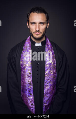 Portrait of young priest. Studio portrait on black background Stock Photo