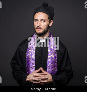 Portrait of young priest. Studio portrait on black background Stock Photo