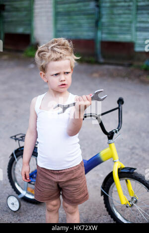 Funny toddler boy repairing his broken bike. Childhood.Cycling Stock Photo
