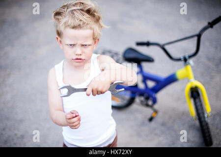 Funny toddler boy repairing his broken bike. Childhood.Cycling Stock Photo