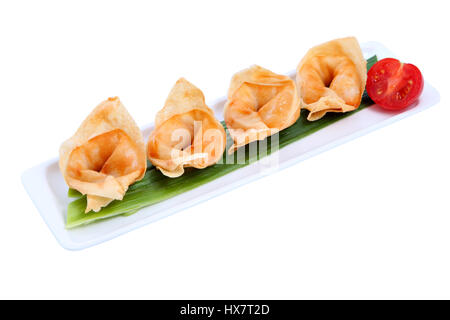 Ruddy Asian dumplings in a row on a long narrow plate, isolated on a white background. Stock Photo