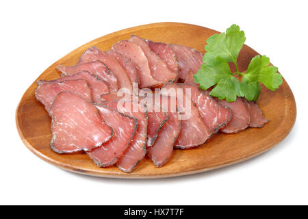 Dry-cured pork slices on wooden plate, isolated on white background. Stock Photo