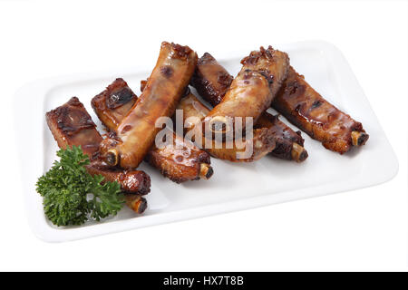 Meat dish of Asian cuisine, grilled Pork Sticky Ribs in hinese Style , lie on a rectangular white plate, isolated on a white background. Stock Photo