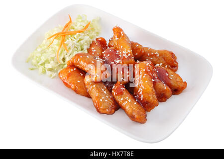 Asian cuisine, Chinese dishes, pork dipped in batter, in a sweet and sour sauce on a white plate, with salad of chopped fresh cabbage, isolated on a w Stock Photo