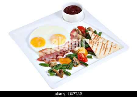English breakfast, fried eggs sunny side up with bacon, vegetables and toast bread, on a square serving plate isolated on white background. Stock Photo